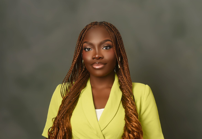 Studio portrait of Ayotundun Christianah Ojelabi wearing a bright lime green dress with long braided hair.