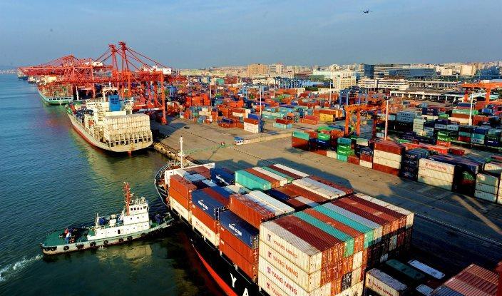 Aerial view of a busy Nigerian shipping port container terminal with cargo ships and cranes.