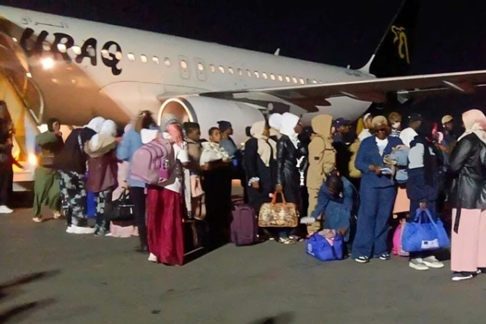 Repatriated Nigerian migrants queueing at night on the tarmac next to a Buraq Air plane at Lagos airport.
