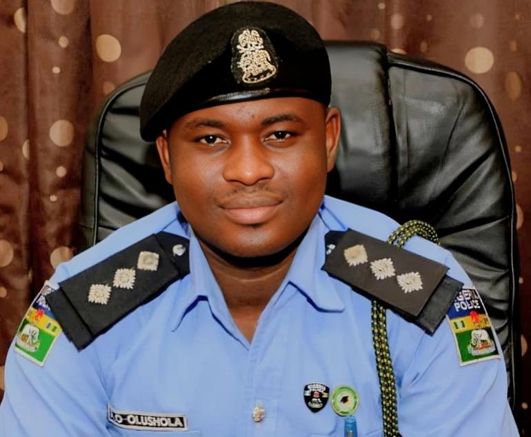 DSP Ayanlade Olushola, the Police Public Relations Officer (PPRO) for the Oyo State Command, wearing a light blue police uniform and black beret while sitting in an office.