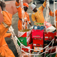 Nigerian ship chandlers in orange overalls loading fresh food crates and supplies onto a vessel.