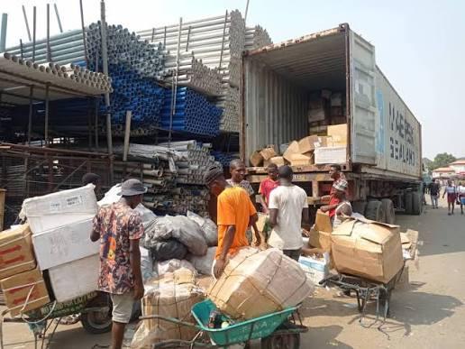 A shipping container truck being offloaded near a warehouse setup in Lagos State during police enforcement operations.