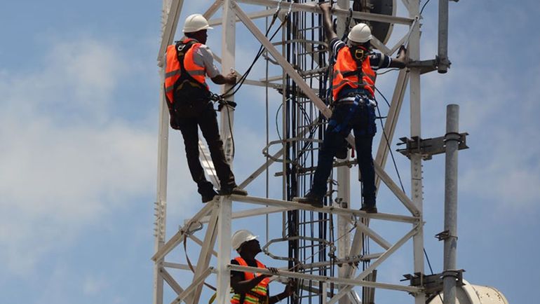 Telecom engineers working on a network mast in Nigeria to maintain internet infrastructure.