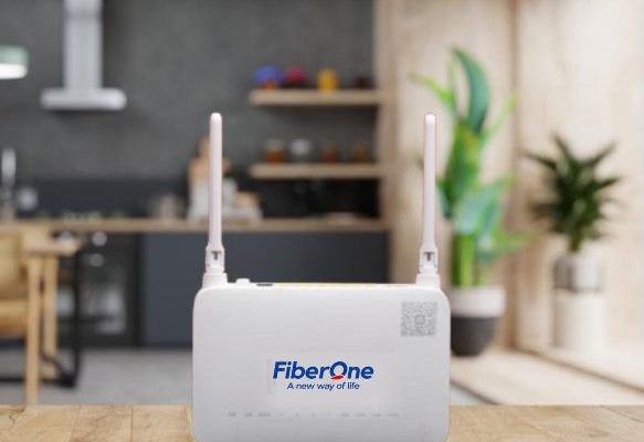 A FibreOne broadband router with two antennas placed on a wooden table in a modern kitchen, representing fibre optic home internet in Nigeria.