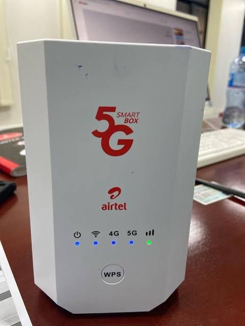A white Airtel 5G Smart Box router with the 5G logo and blue indicator lights on a desk.