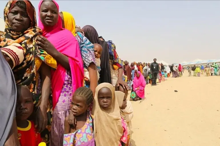 A long line of internally displaced persons (IDPs), mostly women and children, waiting for aid at a camp in Borno State, Nigeria