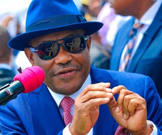 FCT Minister Nyesom Wike wearing a blue fedora and sunglasses during a media brief about Abuja land revocations.