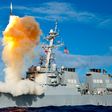 An Arleigh Burke-class guided-missile destroyer, like the USS Mason, launching a vertical interceptor missile from its deck during a naval engagement.