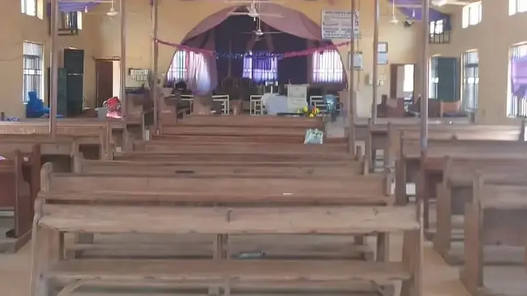 Empty interior of a local ECWA church in Nigeria with wooden pews and a draped altar.