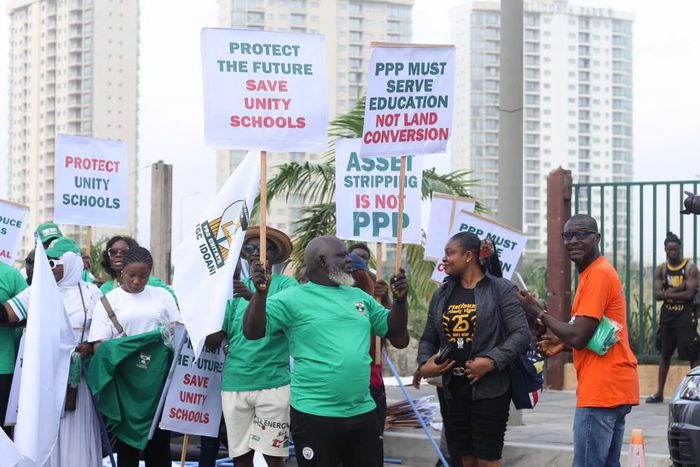group of Nigerian alumni and protesters holding placards with "Protect the Future, Save Unity Schools" and "Asset Stripping is Not PPP" written on them.