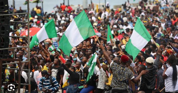 A crowd of Nigerian youths waving the national flag during a peaceful protest or gathering.