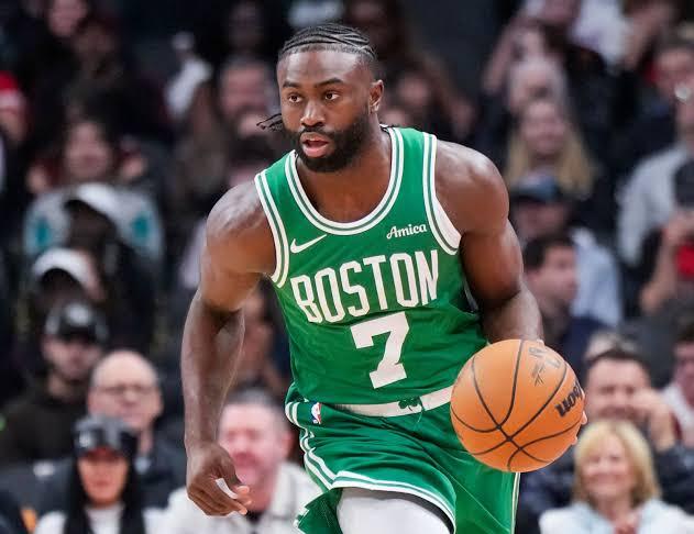 Boston Celtics forward Jaylen Brown dribbling a basketball down the court during an NBA game, wearing a green number 7 jersey with a focused expression.