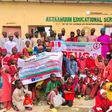 NDLEA officials and students of At-Ta'awuun Educational Services posing with "War Against Drug Abuse" banners during a drug awareness campaign in Nigeria.