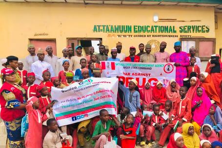 NDLEA officials and students of At-Ta'awuun Educational Services posing with "War Against Drug Abuse" banners during a drug awareness campaign in Nigeria.