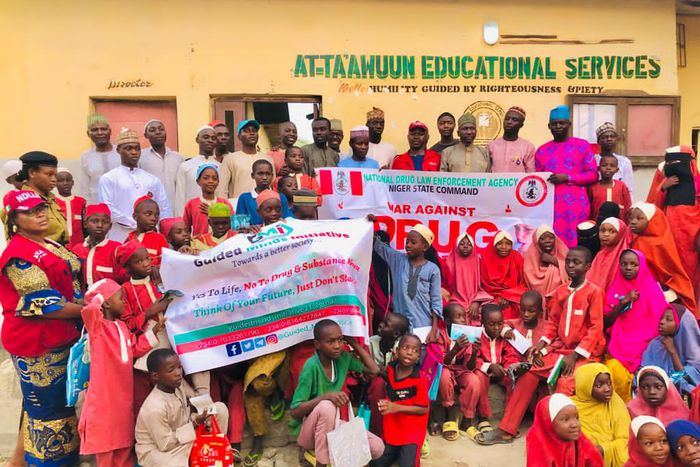 NDLEA officials and students of At-Ta'awuun Educational Services posing with "War Against Drug Abuse" banners during a drug awareness campaign in Nigeria.