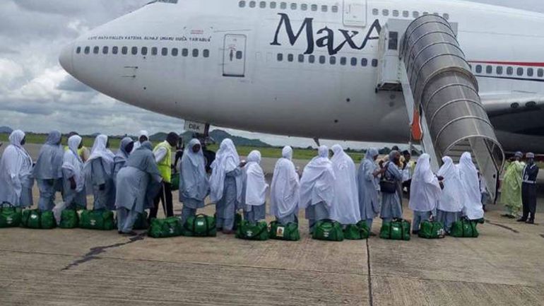 A line of Nigerian Hajj pilgrims in white hijabs boarding a Max Air plane at the airport for the 2026 pilgrimage.
