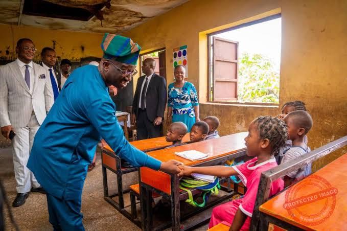 Edo State government visiting a primary school classroom with young students sitting at wooden desks in Nigeria.