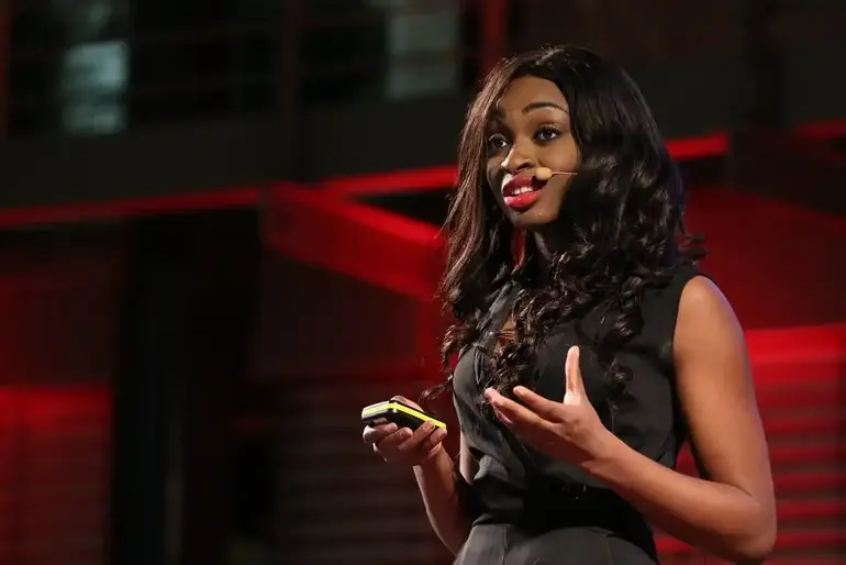 Dr Ola Brown speaking at a business conference with a microphone and remote clicker.