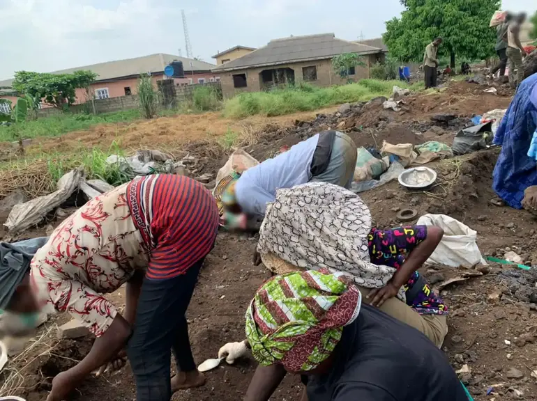 People digging and searching through dirt at an informal dumpsite in Lagos.