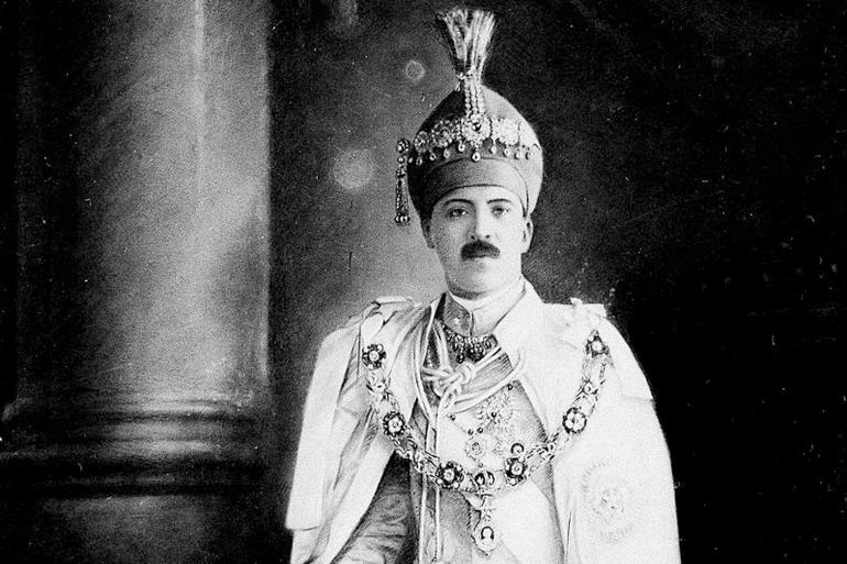 A historical black and white photograph of Mir Osman Ali Khan, the Nizam of Hyderabad, wearing ceremonial robes and a jewel-encrusted headpiece.