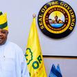 Osun State Governor Ademola Adeleke posing in his office alongside the state seal and flag.