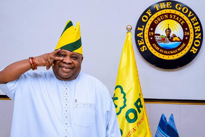 Osun State Governor Ademola Adeleke posing in his office alongside the state seal and flag.