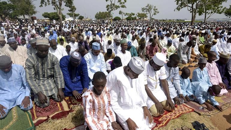 Crowd of Nigerian Muslim faithful performing Eid prayers at an open prayer ground during Sallah.