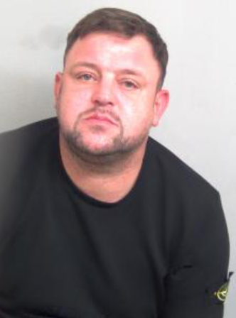 Police mugshot of Jakub Jan Konkel, a 40-year-old Polish national with short brown hair and light stubble, wearing a black shirt.