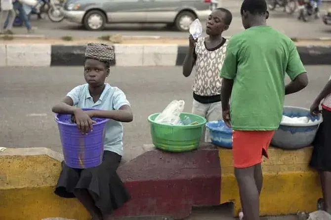 Vulnerable out-of-school children hawking items on a street curb in Nigeria.