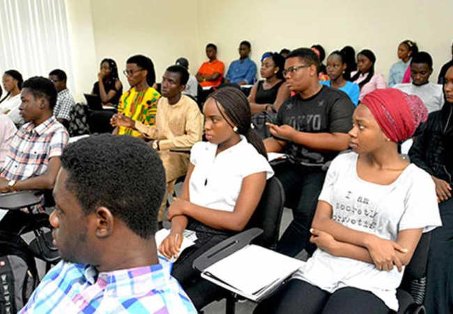 University students sitting in lecture chairs inside a classroom, attending a academic session.