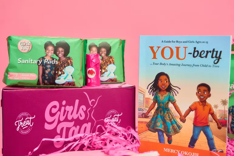 The contents of the ₦25,000 Girls Tag period box featuring sanitary pads and Mercy Johnson's educational book titled Youberty.