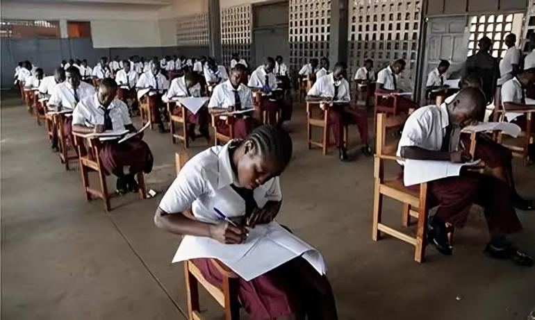A large group of candidates concentrating on their examination papers at a designated testing centre.