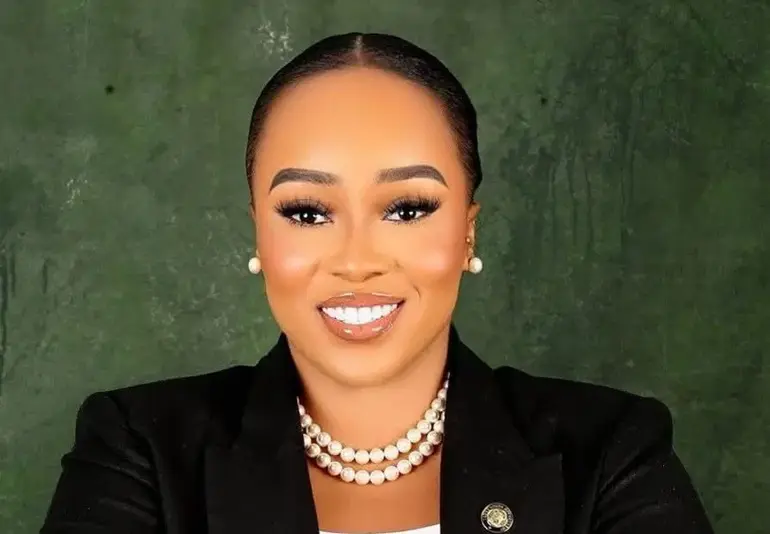Professional portrait of Barrister Barakat Olawunmi Odunuga-Bakare, BBA, smiling warmly in a corporate black blazer and pearl necklace against a textured green backdrop.