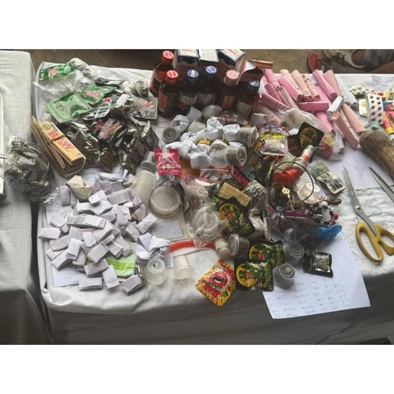 A collection of suspected illicit drugs, syrup bottles, and wrapped packets recovered during the police operation.