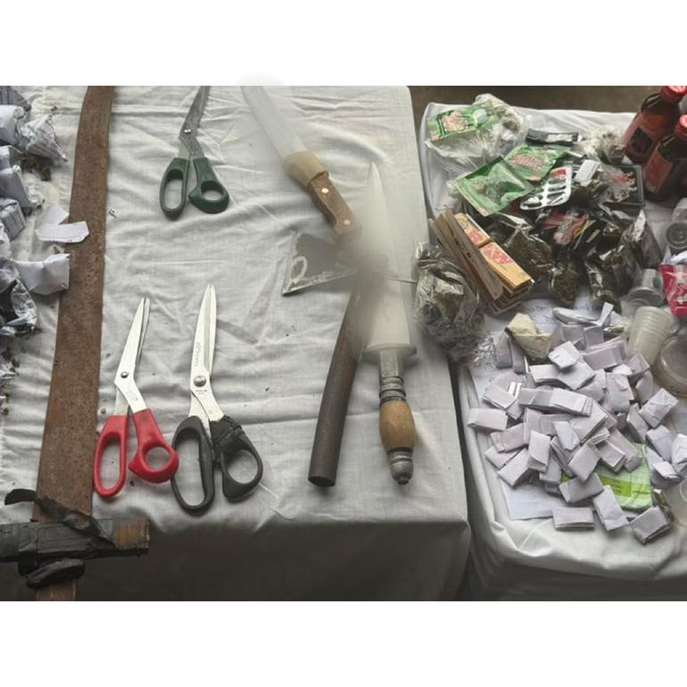 Exhibits, including scissors, knives, and suspected illicit substances, are displayed on a table.
