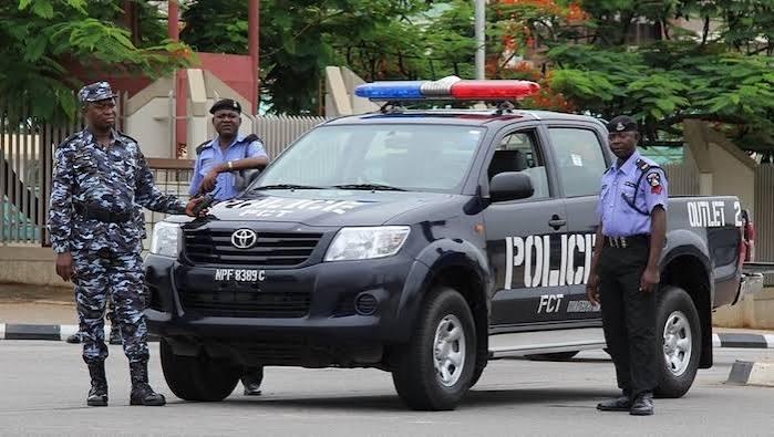 Nigeria Police Force officers standing next to an official FCT command patrol vehicle.