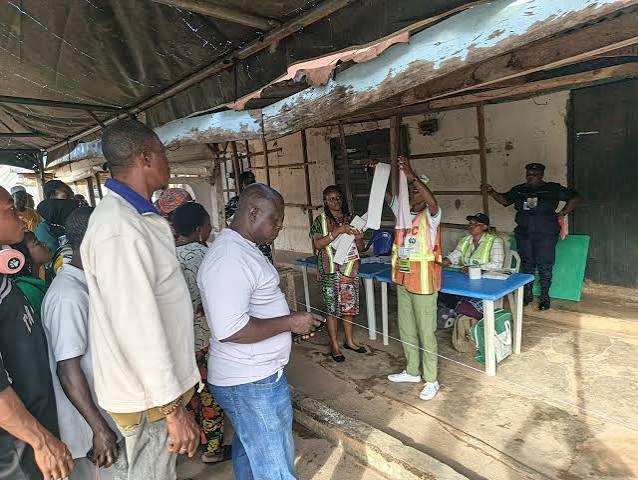 Voters waiting in line at a local polling unit while INEC electoral officials verify documents under a canopy during the recent Ekiti governorship election.