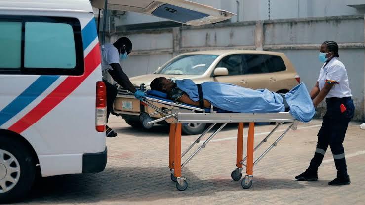 Medical first responders moving a patient on a stretcher into an ambulance in Nigeria.