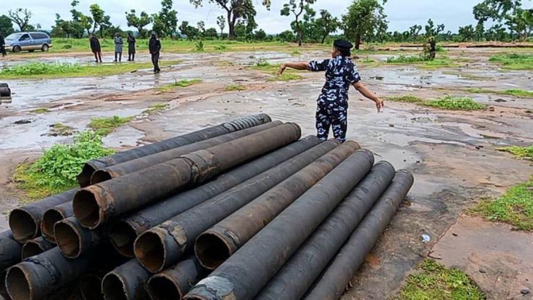 A Nigeria Police officer inspecting a pile of recovered NNPCL pipes at the crime scene along Yola-Numan road.