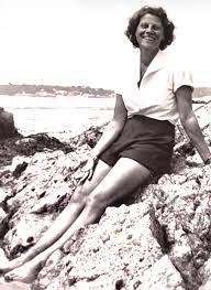 Black and white historic photo of a young Ethel Caterham, the future world's oldest person, smiling and sitting on rocky shores.