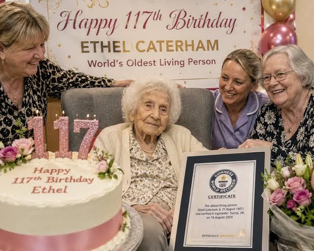 117-year-old Ethel Caterham celebrating her birthday with a large cake, care home staff, and her Guinness World Records certificate for world's oldest living person.