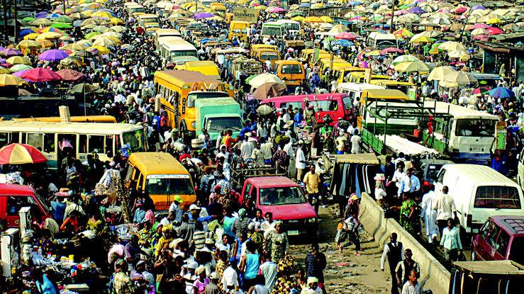 A busy open-air market in Lagos, Nigeria, with people shopping under colourful umbrellas.