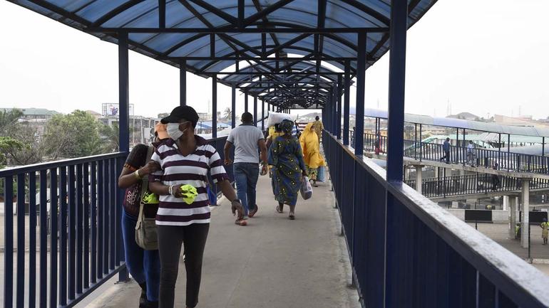 Commuters walk along the protected elevated walkway of a Lagos pedestrian overpass.