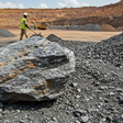 A large raw lithium and polymetallic ore mineral sample sitting on an active mining field in Nigeria.