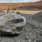 A large raw lithium and polymetallic ore mineral sample sitting on an active mining field in Nigeria.