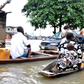 Commuters, including a woman with a child, using a canoe to bypass a submerged minivan on a flooded road in Owode-Elede, Lagos.
