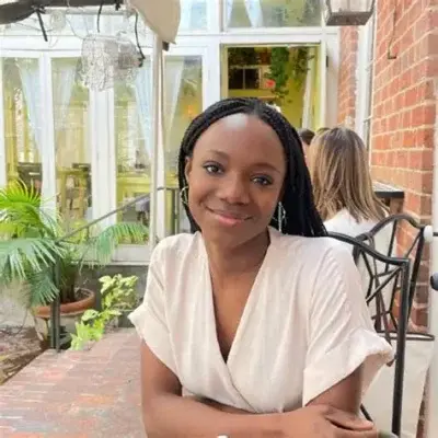 Yinka Ogunbiyi, founder and CEO of HaloBraid, wearing box braids and sitting outdoors in a patio setting.