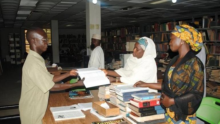 Non-academic university library staff assisting students at a circulation desk in a Nigerian federal university