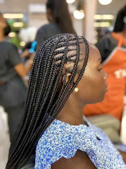 Side profile of a woman displaying intricate, neatly styled protective box braids in a salon.