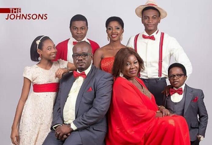 Official cast portrait of the beloved family sitcom The Johnsons, featuring Chinedu Ikedieze, Charles Inojie, the late Ada Ameh, and the rest of the onscreen family posing in coordinated formal wear.